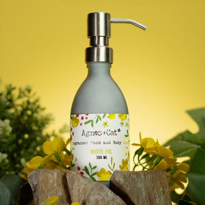 Hand soap bottle with pump labeled 'Agnes + Cat' on a yellow background with flowers.