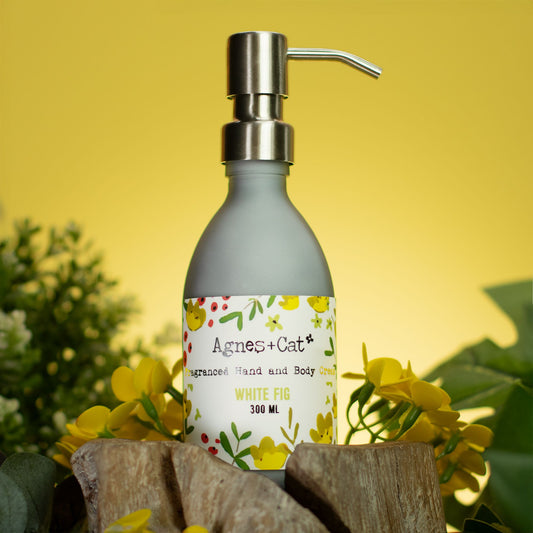 Hand soap bottle with pump labeled 'Agnes + Cat' on a yellow background with flowers.