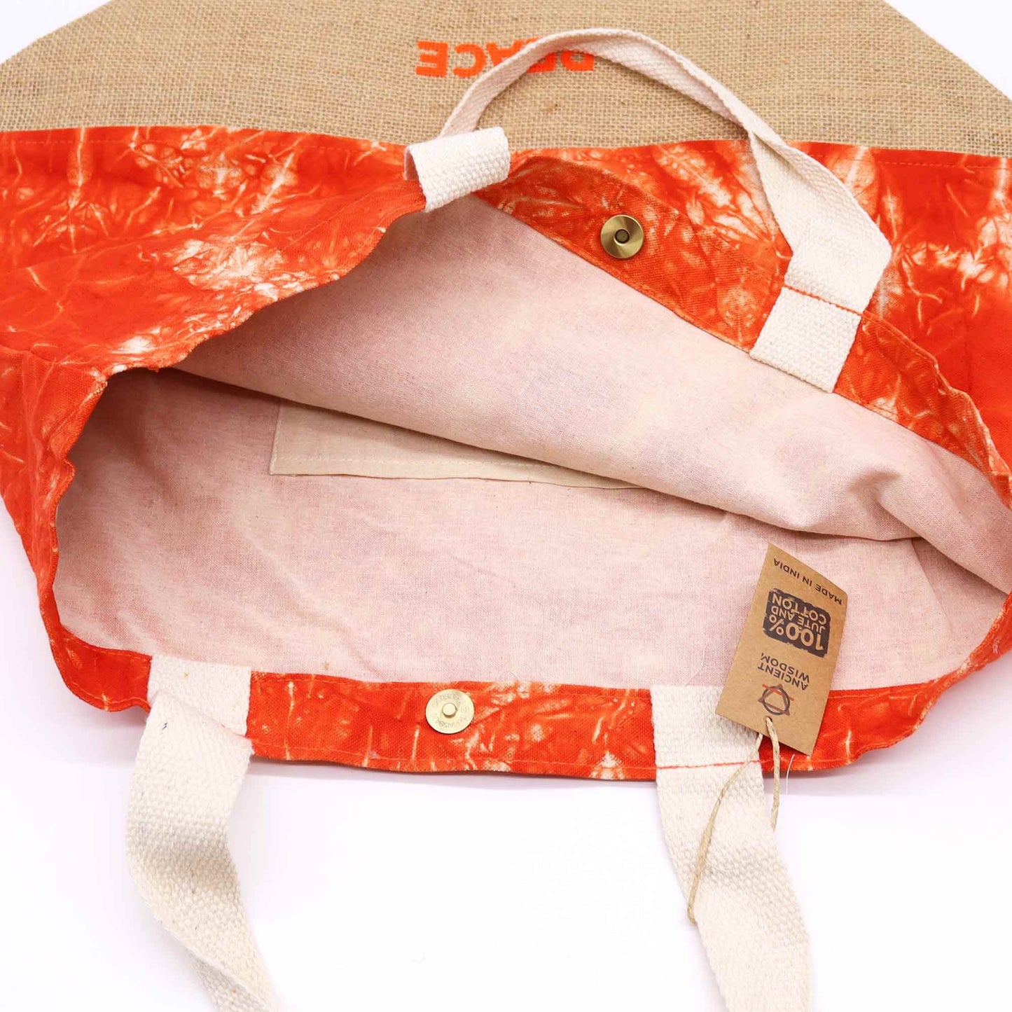 Close-up of a jacket with orange and beige pattern, visible brand tag, and beige hat on a white background.