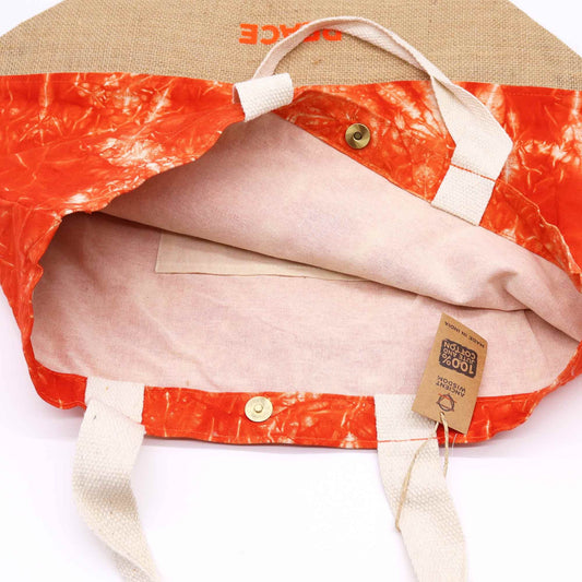 Close-up of a jacket with orange and beige pattern, visible brand tag, and beige hat on a white background.