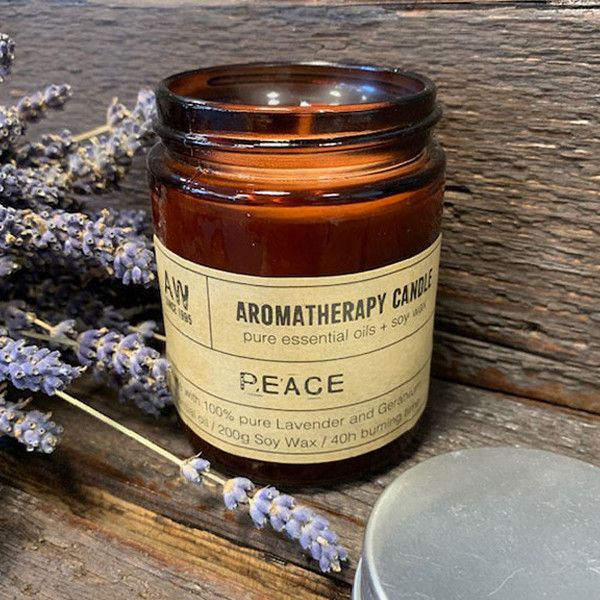 Aromatherapy candle labeled 'Peace' with lavender flowers on a wooden surface