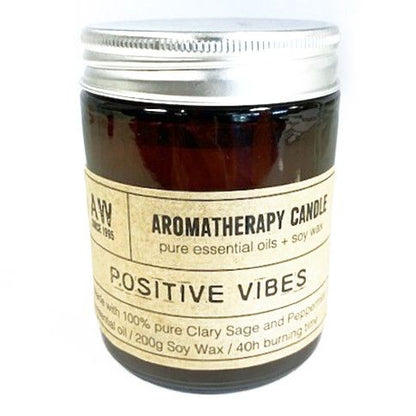 Aromatherapy candle labeled 'Positive Vibes' with a silver lid on a white background