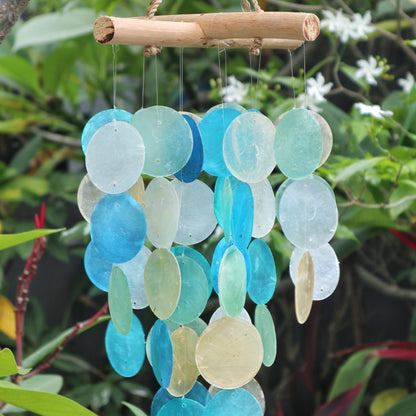 Decorative wind chime with blue and green circular discs hanging against a natural background.