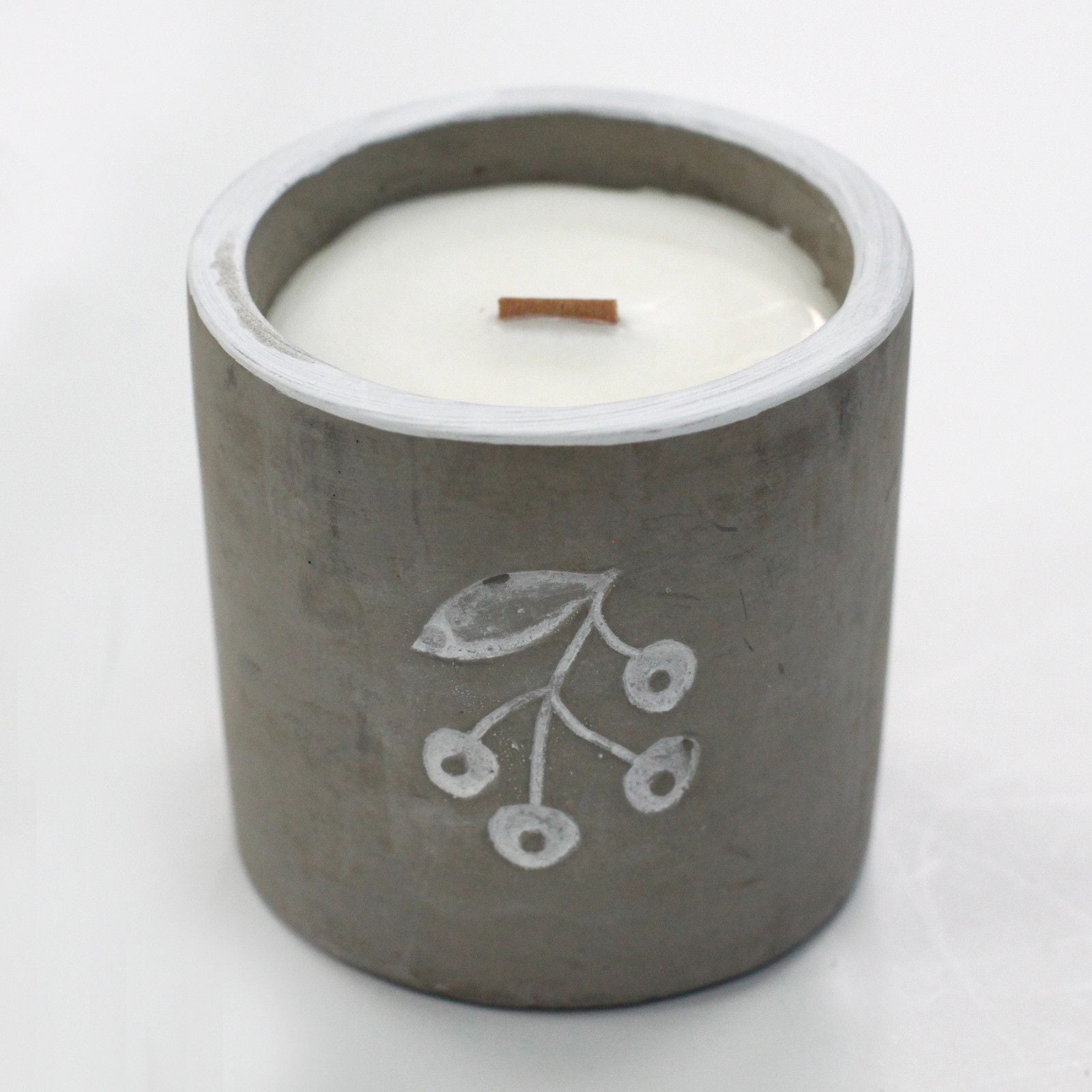 Candle in a concrete holder with a leaf design on a white background
