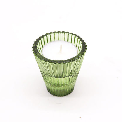 Green ribbed candle holder with a white candle on a white background
