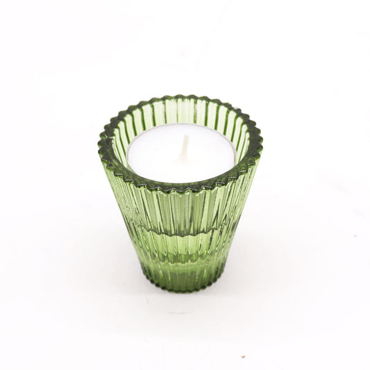 Green ribbed candle holder with a white candle on a white background