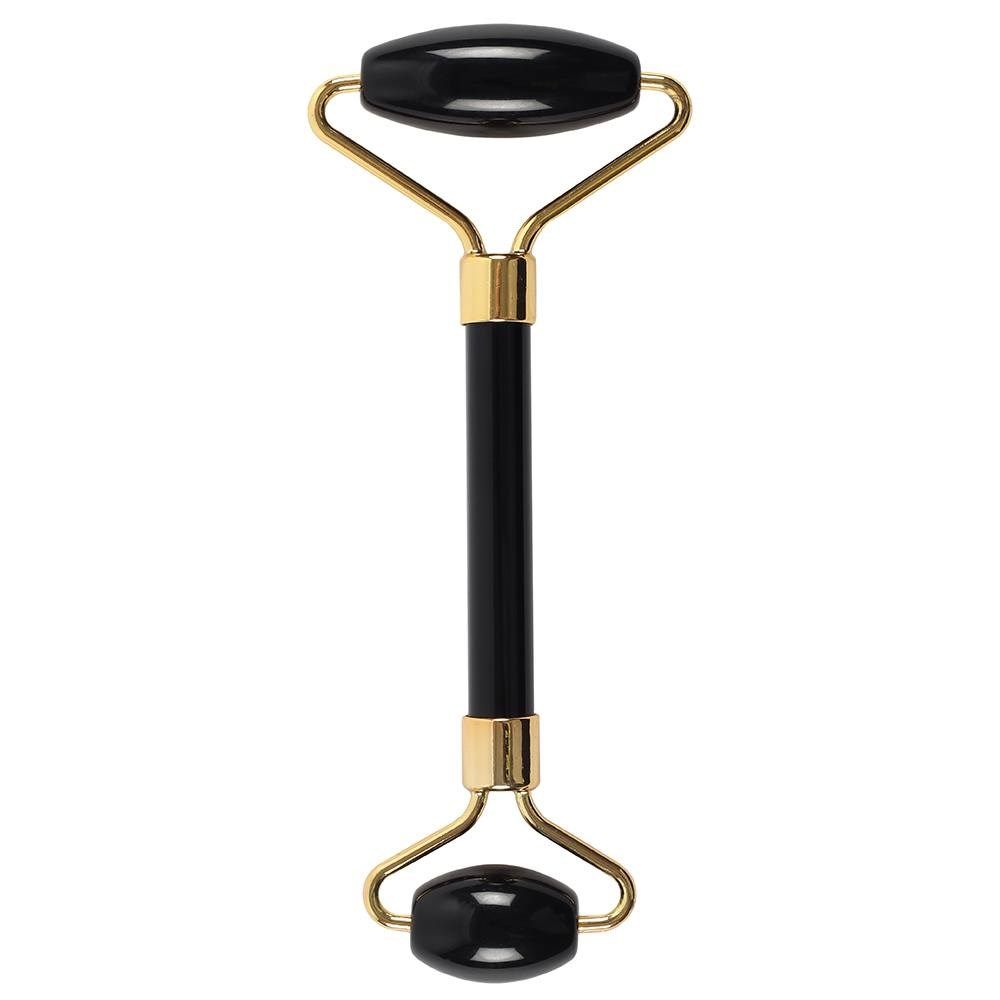 Black and gold facial roller on a white background