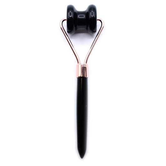 Black and rose gold facial roller on a white background