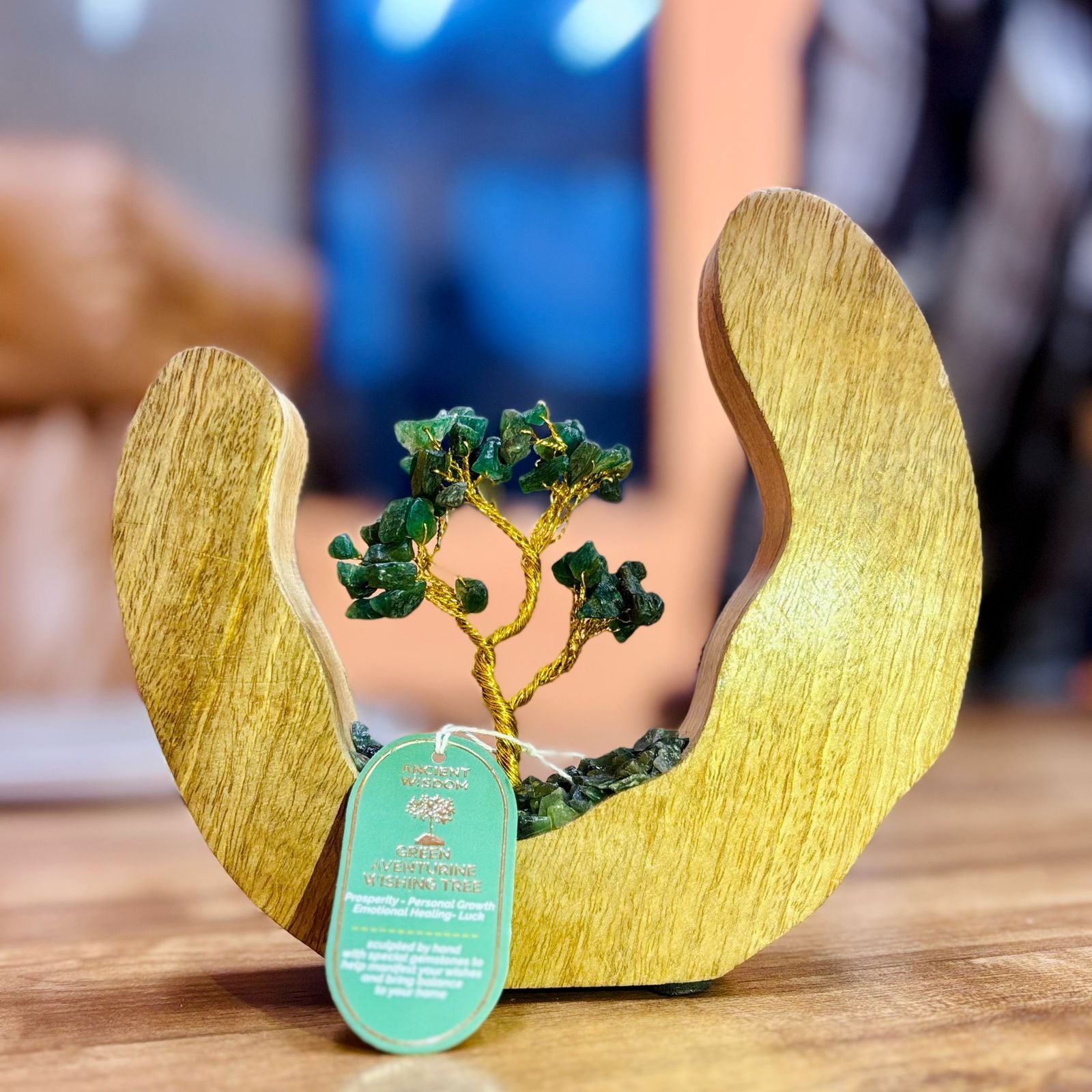 Decorative item with a tree sculpture inside wooden wings on a table.