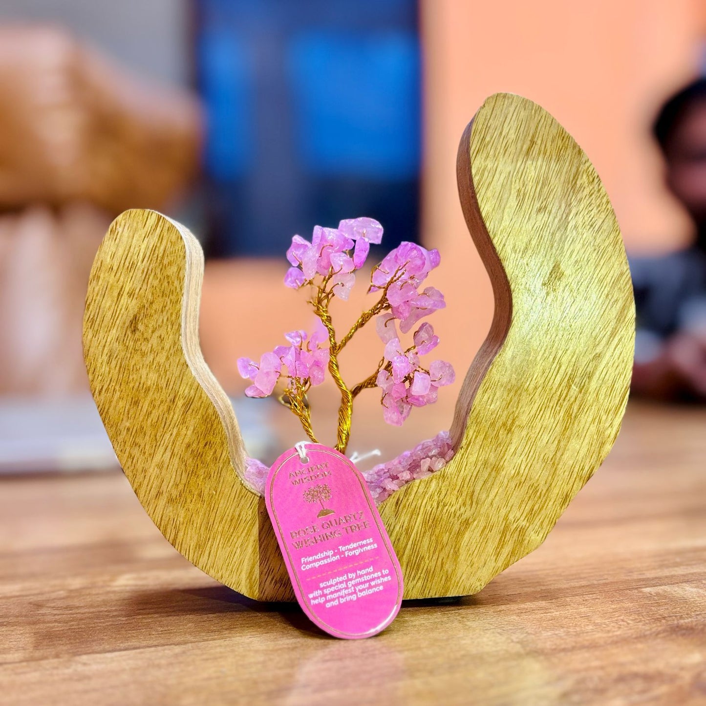 Wooden sculpture with pink decorative elements on a wooden surface