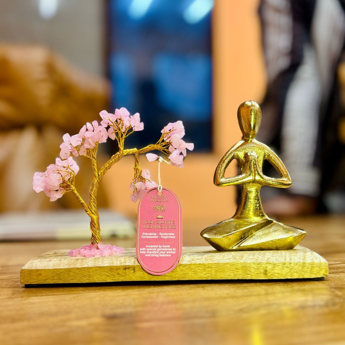 Decorative item with gold tree and figure on a wooden base, blurred background