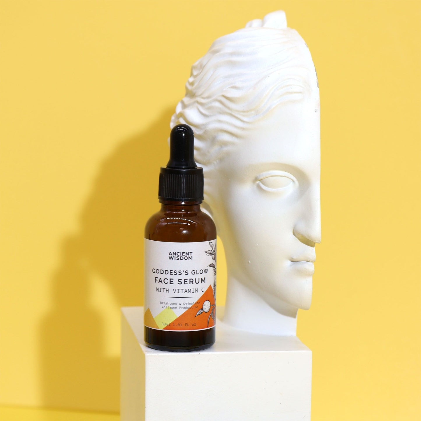Face serum bottle labeled 'Goddess's Glow Face Serum' on a yellow background with a white sculpture of a face.