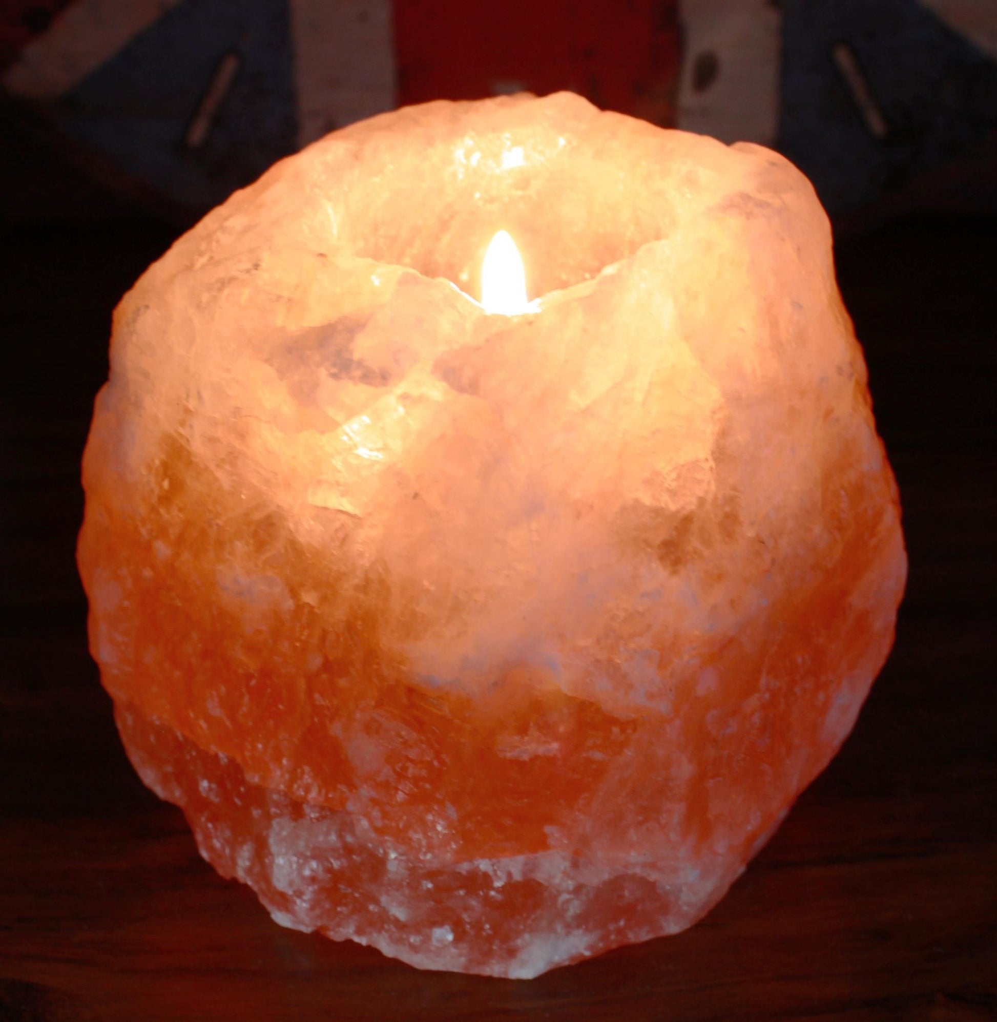 Candle inside a textured, orange-colored salt lamp on a dark background