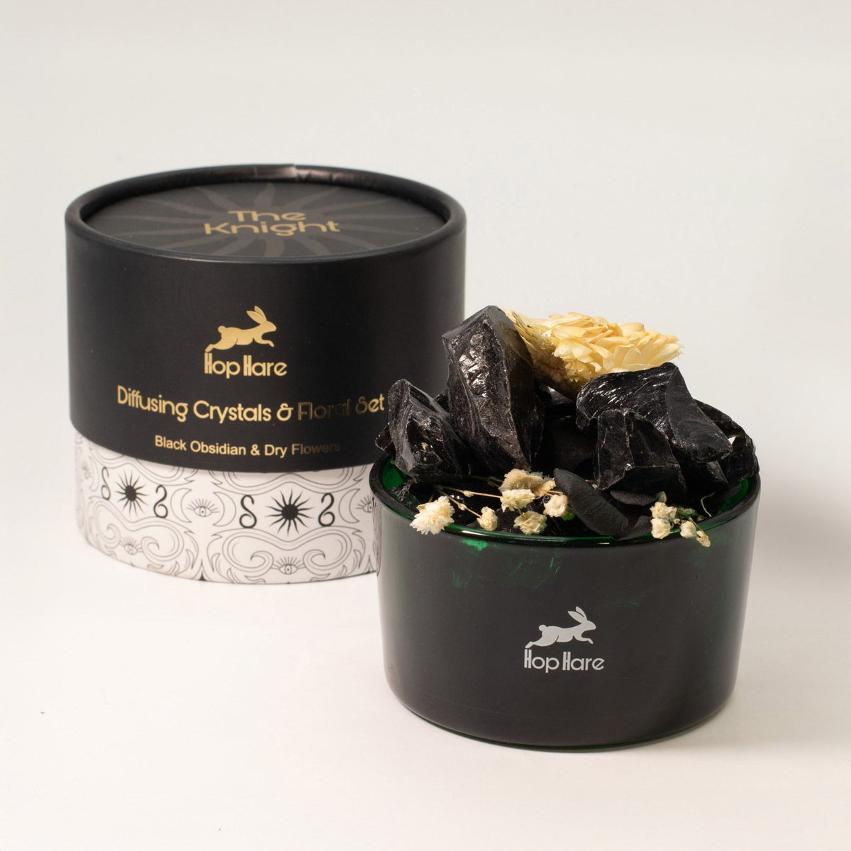 Black container with crystals and flowers, branded 'Illopilare', on a white background