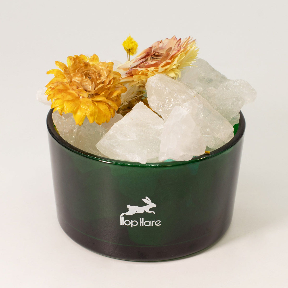 Green container with crystals and flowers on a white background