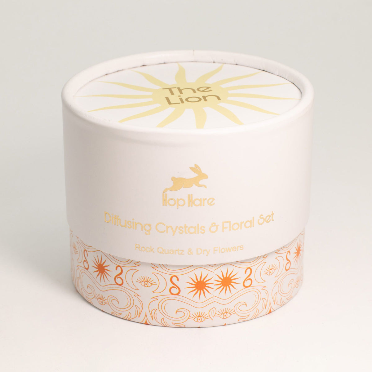Round white container with gold and orange design and text on a light gray background