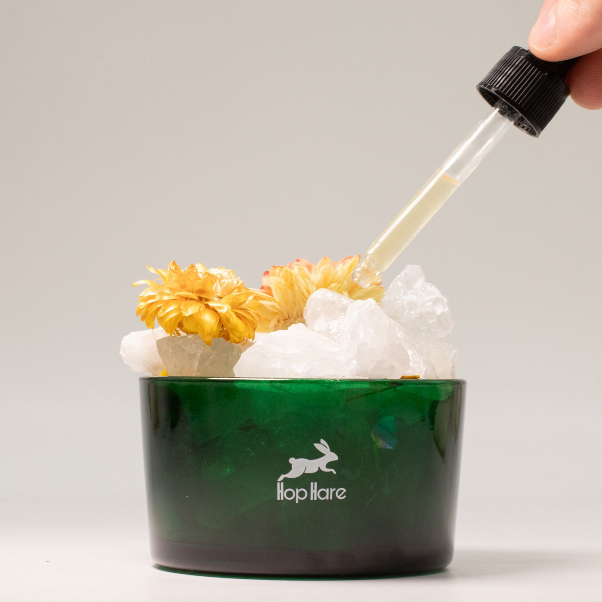 Green container with flowers and ice, dropper adding liquid, ' flopHare' brand visible