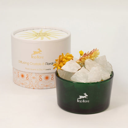 Green container with white crystals and yellow flowers next to a branded white lid on a light background