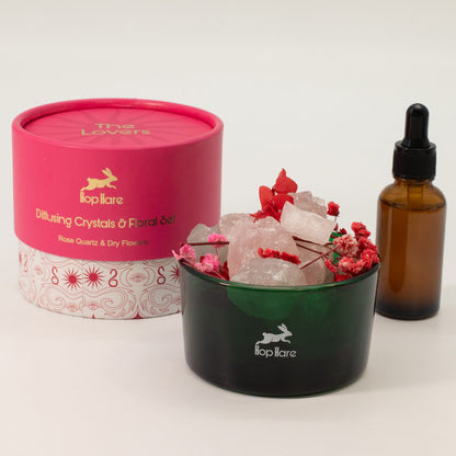 Diffusing crystals with flowers in a container, pink box, and brown bottle on a white background
