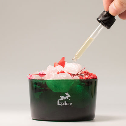 Green container with ice and red flowers, dropper adding liquid, brand 'flop hare' visible