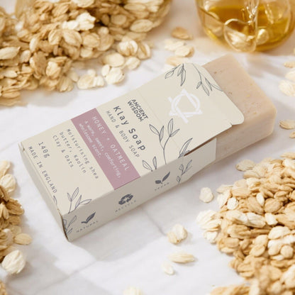 Bar of soap with a label on a surface with oats and honey.