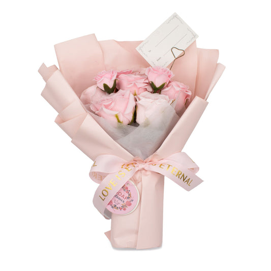Bouquet of pink roses wrapped in light pink paper with a decorative bow on a white background