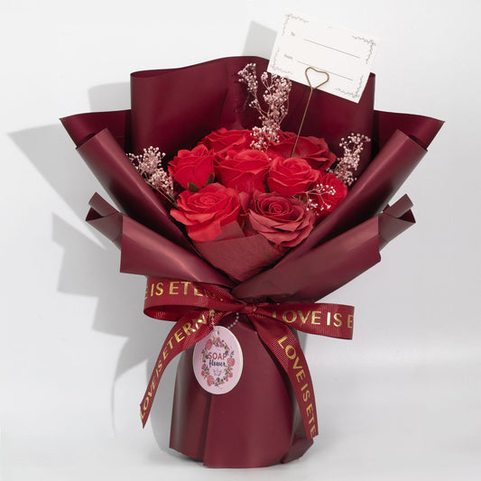 Bouquet of red roses wrapped in burgundy paper with a decorative ribbon on a white background