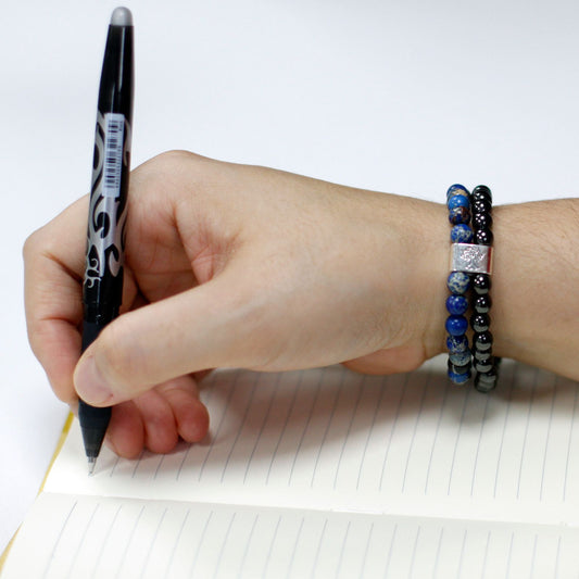 Hand holding a pen with a bracelet on a white background