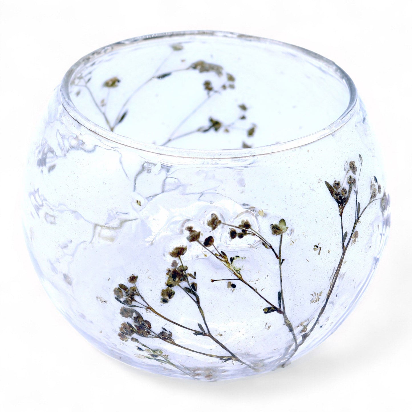 Clear glass bowl with dried flowers on a white background