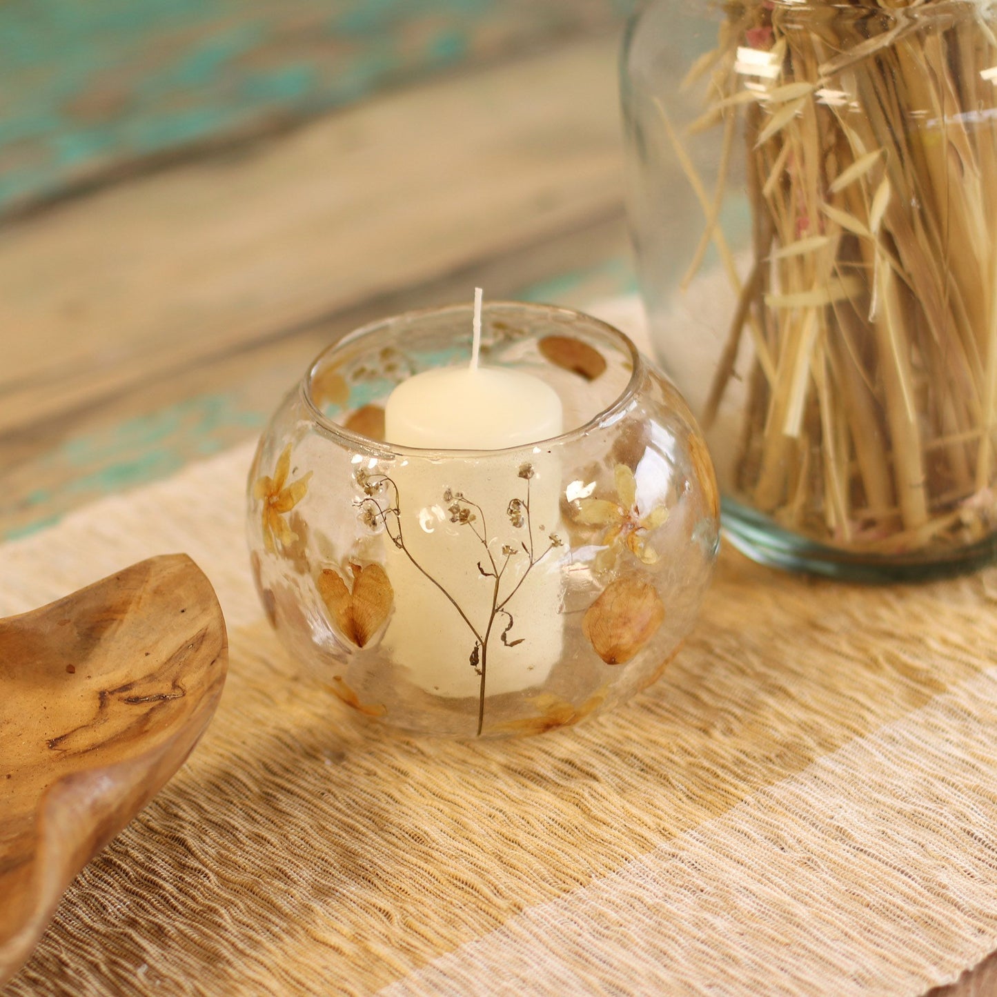 Candle in a glass holder with natural elements on a wooden surface
