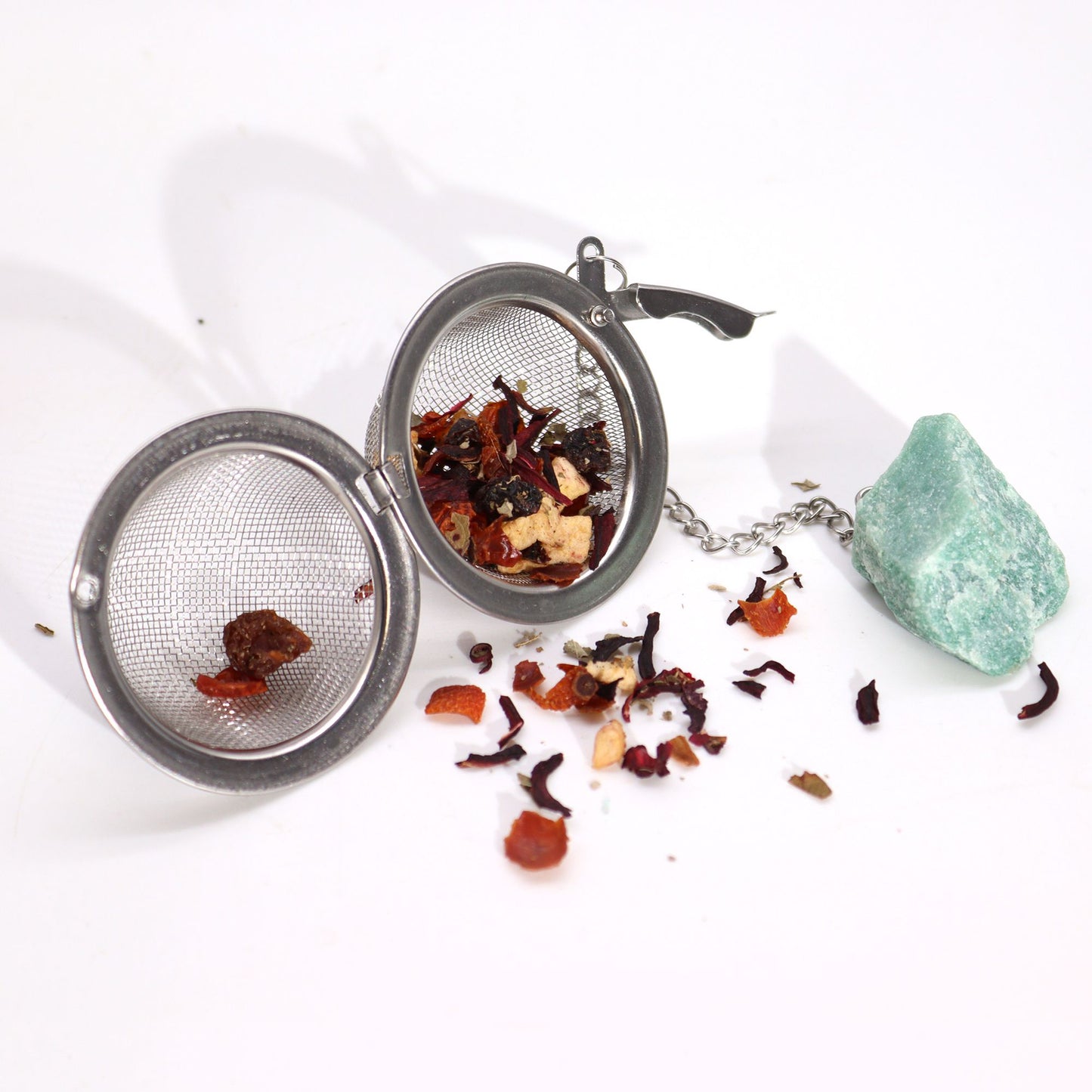 Tea ball with loose tea leaves on a white background