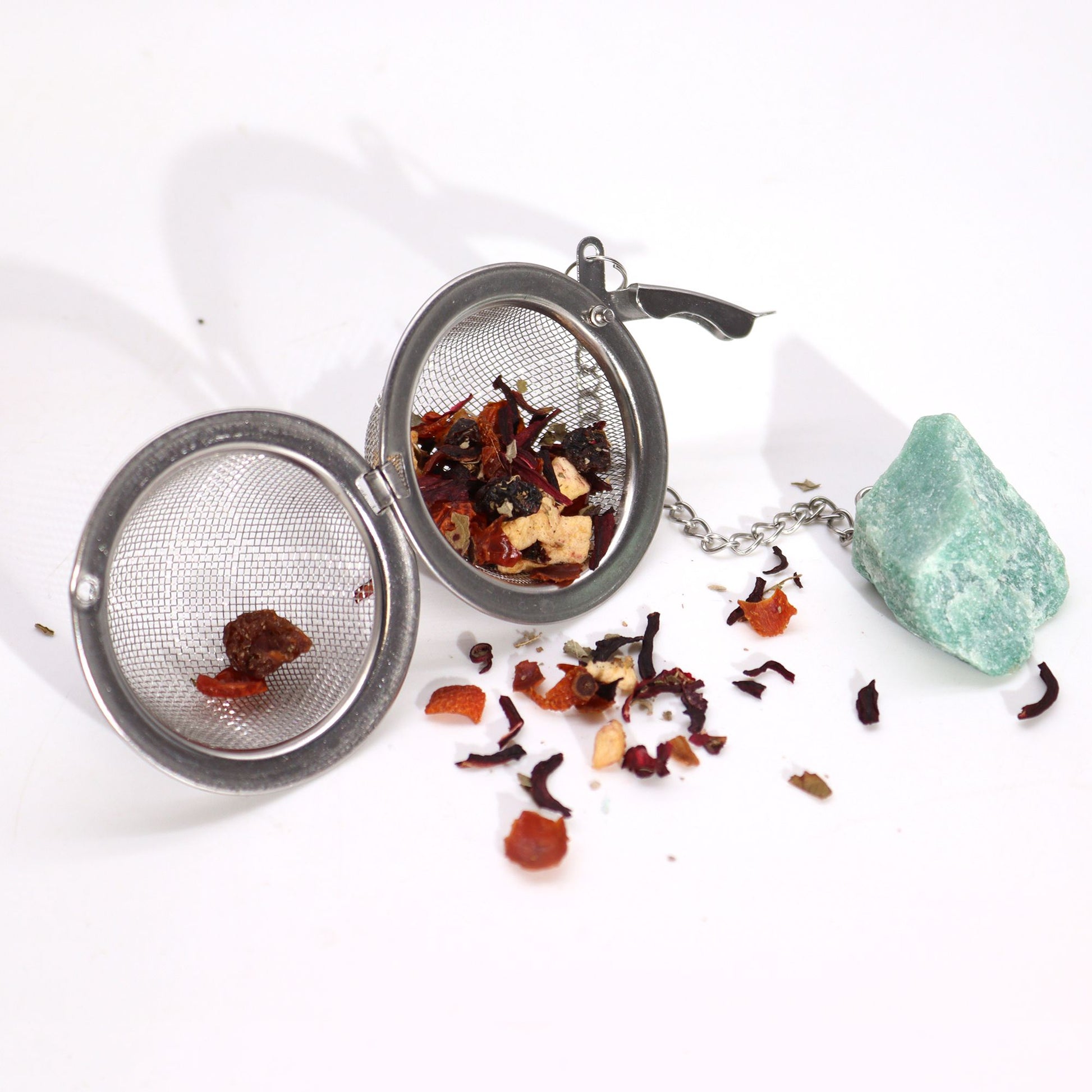 Tea ball with loose tea leaves on a white background