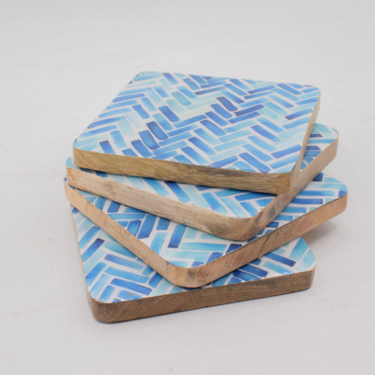 Set of four blue patterned coasters with wooden edges on a light gray background