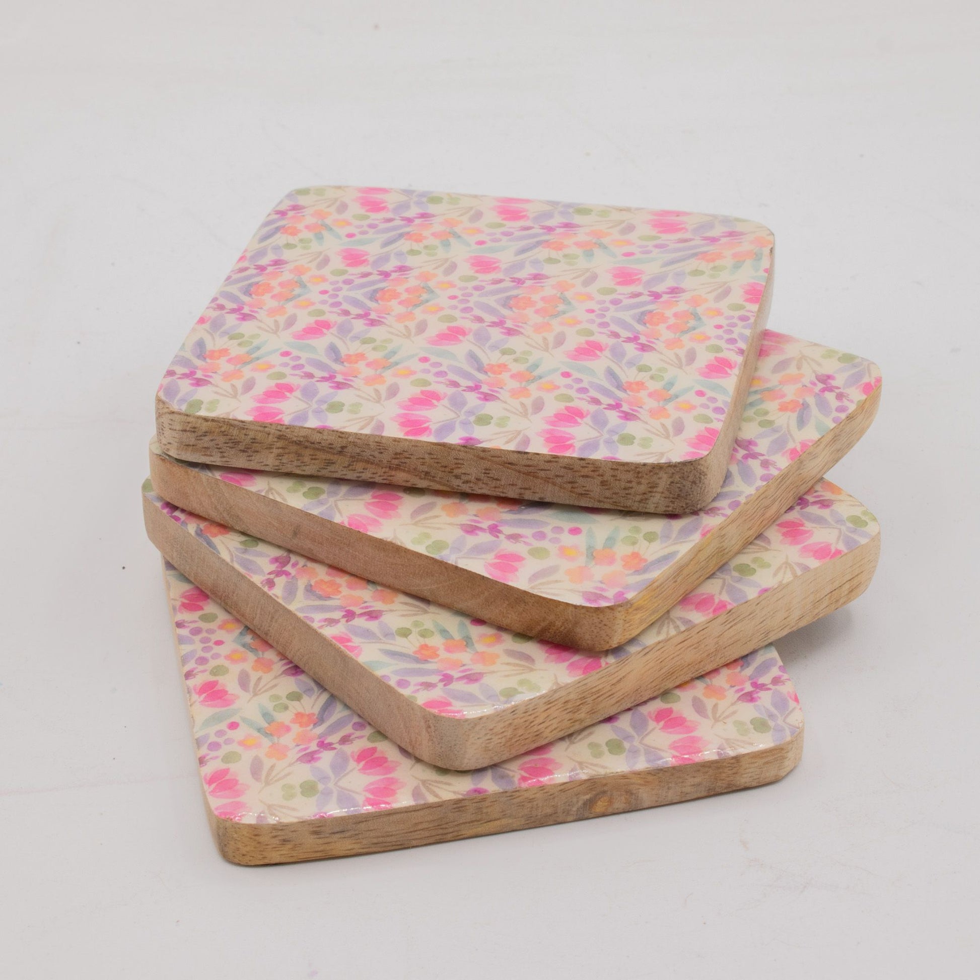 Set of four floral patterned coasters on a light gray background