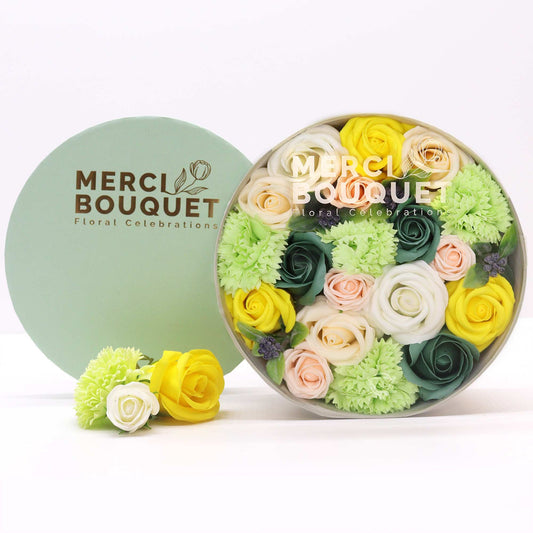 Floral arrangement in a round box with 'Merci Bouquet' branding on a white background