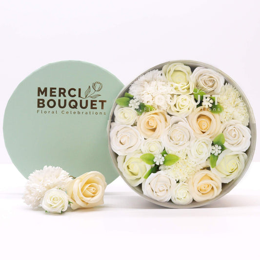 Round box of flowers with 'Merci Bouquet' branding on a white background