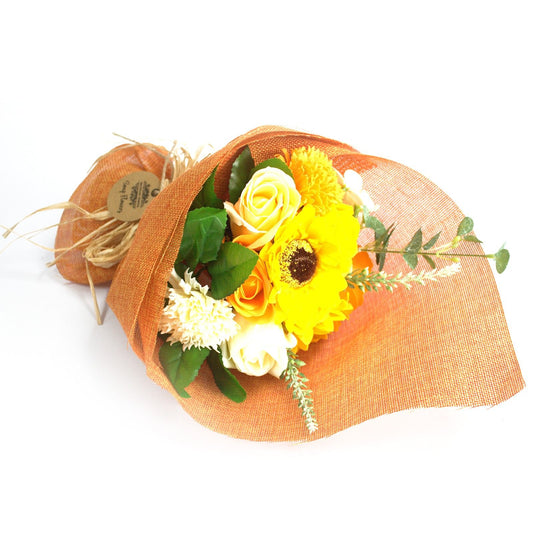 Bouquet of yellow flowers wrapped in brown paper on a white background