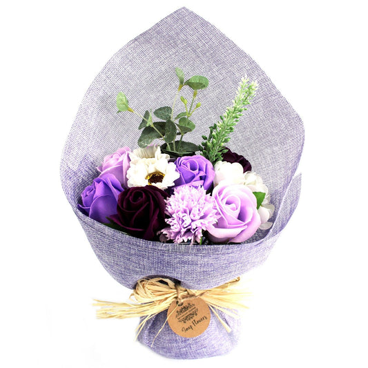 Bouquet of purple and white flowers wrapped in gray paper with a gold ribbon on a white background