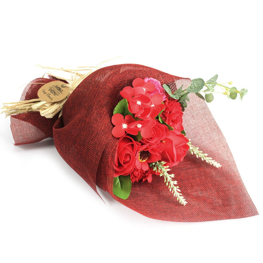 Bouquet of red flowers with green leaves and a red wrap on a white background