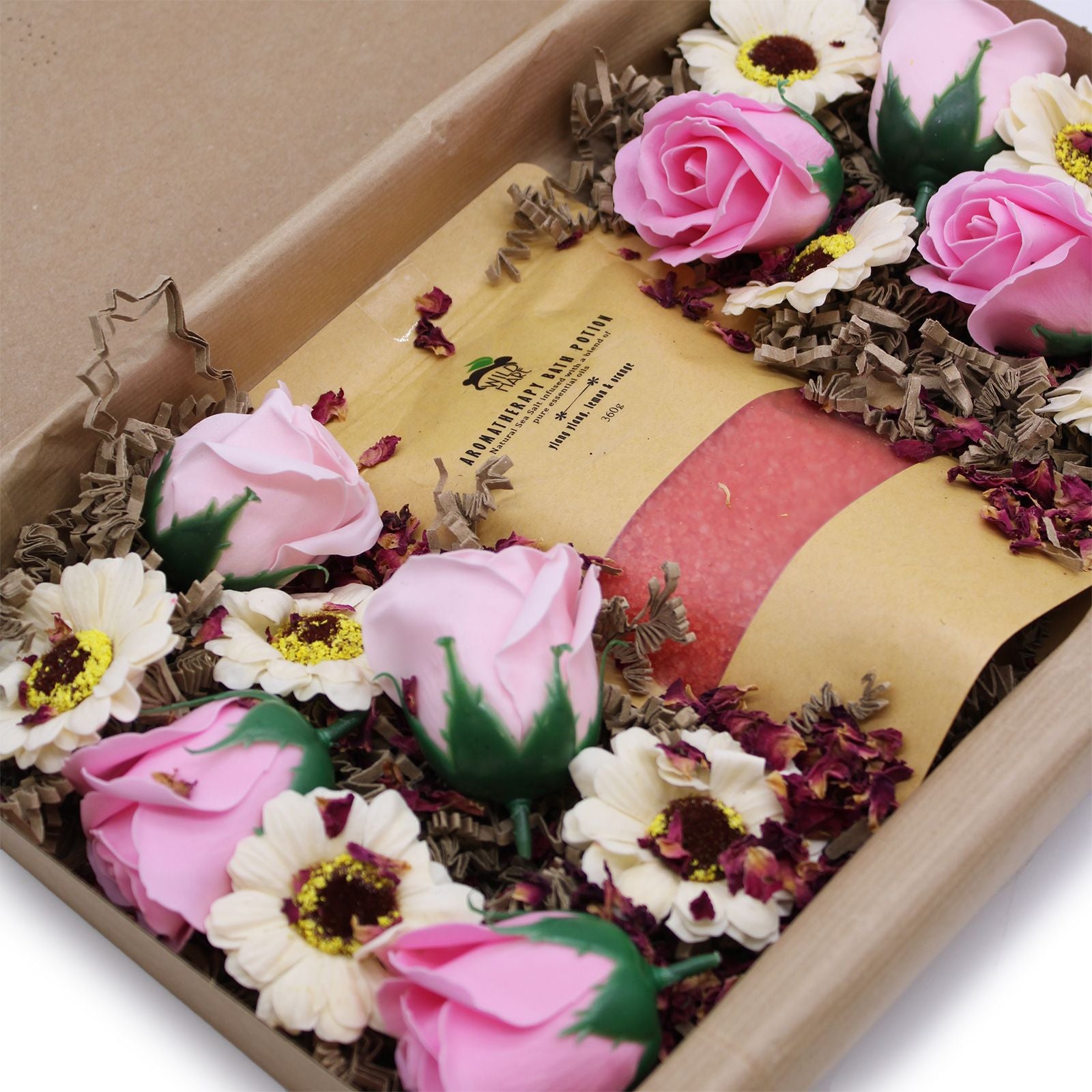 Bottle of perfume surrounded by pink and white flowers in a decorative box.