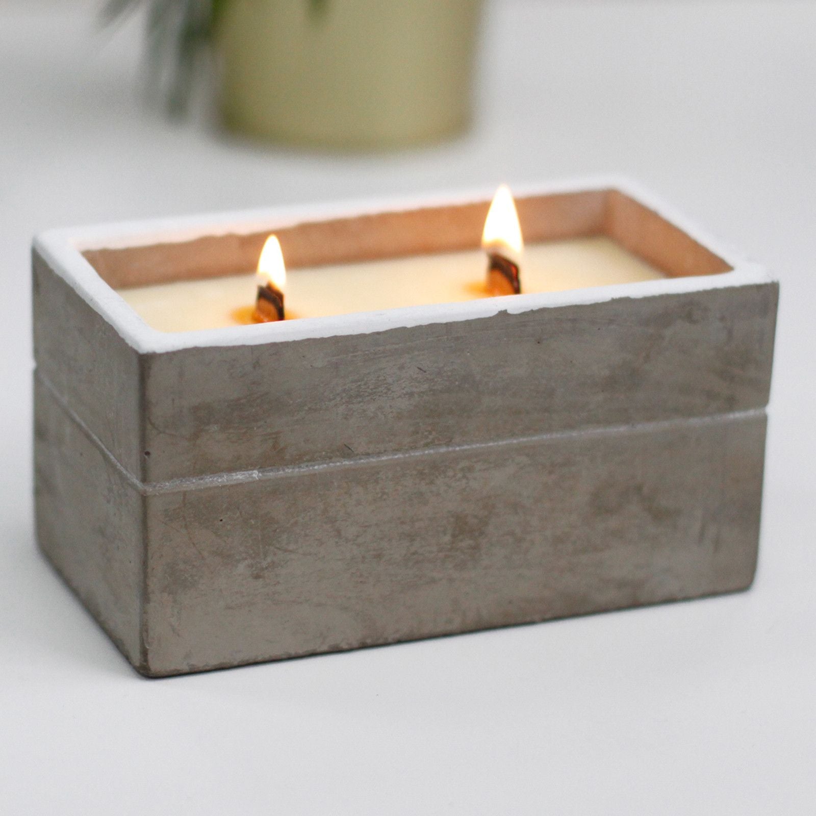Cement box with two lit candles on a light background