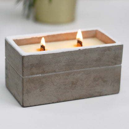Cement box with two lit candles on a light background