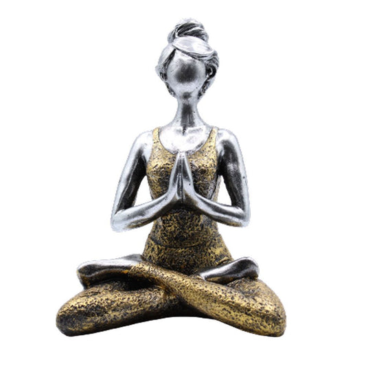 Statue of a woman in a yoga pose with a gold and silver finish on a white background