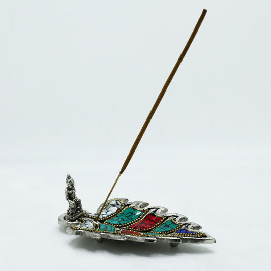 Decorative incense holder with a feather design on a white background