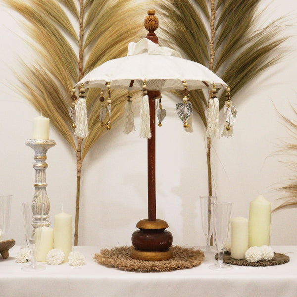 Decorative lamp with tassels on a table with candles and flowers against a feathered wall.