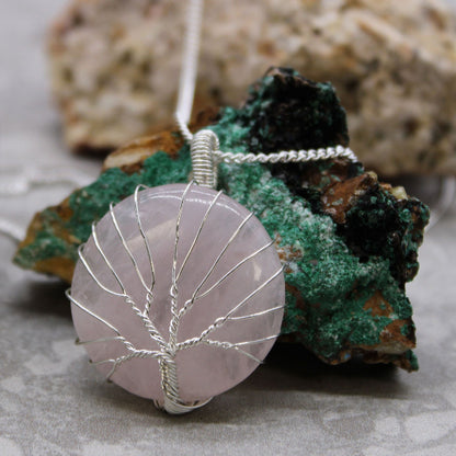 Necklace with a pink stone pendant featuring a silver tree design on a rock background