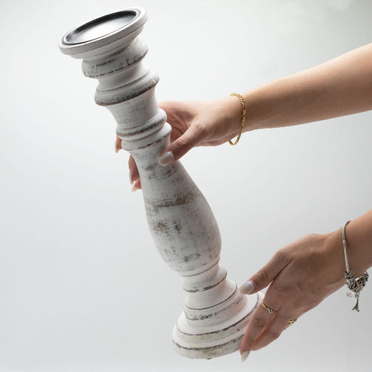 Person holding a textured white candle holder against a light background