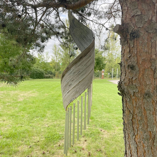 Wooden chime hanging from a tree in a park setting