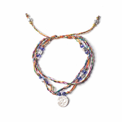 Multicolored braided bracelet with a silver charm on a white background