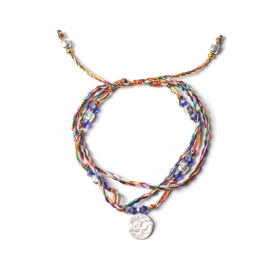 Multicolored braided bracelet with a silver charm on a white background
